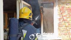 пожежа, пожежник, рятувальник гасить вогонь у будинку